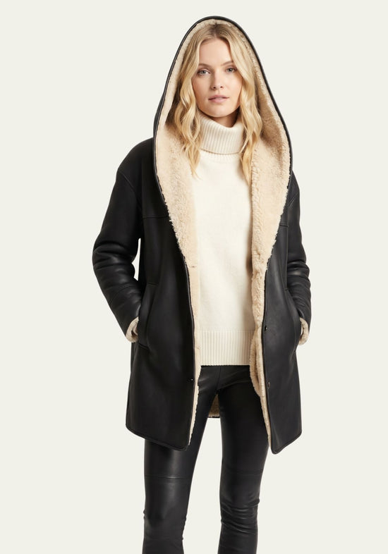 Black women’s sheepskin jacket with hood worn open, with light sheepskin lining and pockets visible.