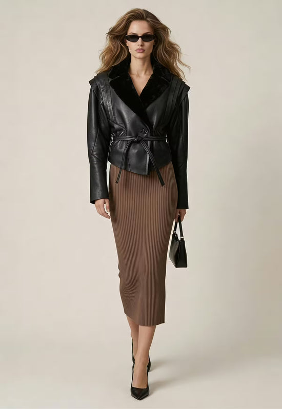 Black women's sheepskin jacket worn by a model with a midi skirt and heels.