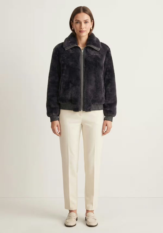 Women's shearling sheepskin jacket in anthracite, worn frontally with light trousers
