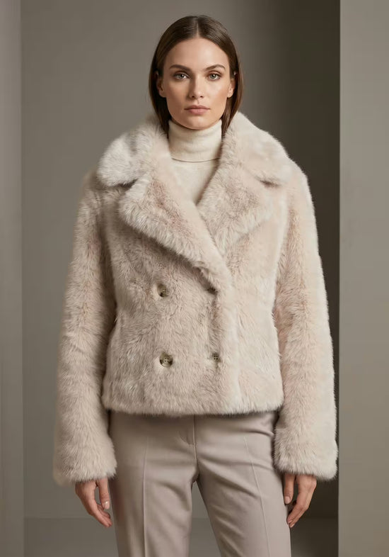 Women’s sheepskin jacket in cream-beige, shown in a portrait view against a dark background.