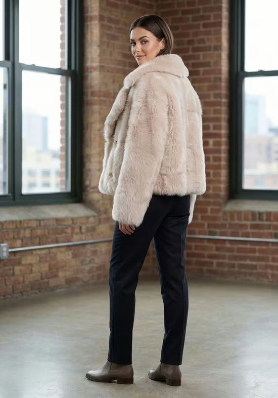 Cream-beige sheepskin jacket worn by the model in a side view from the back.