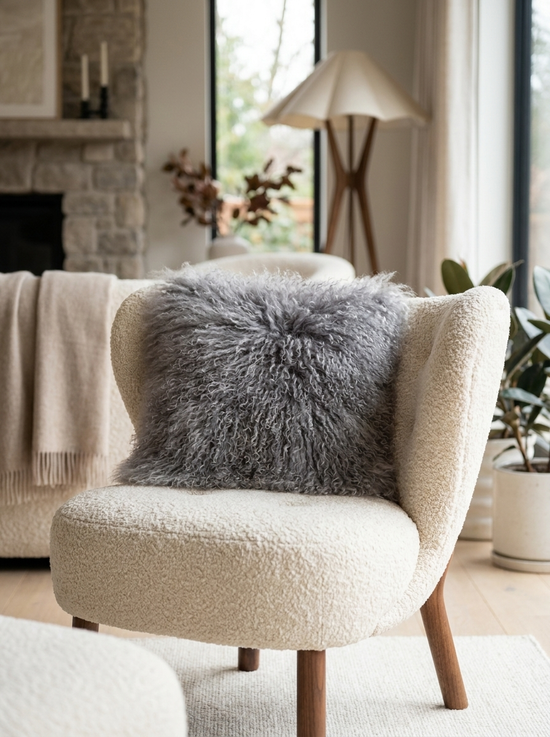 Grey Tibetan sheepskin cushion arranged on a light chair in a living room.