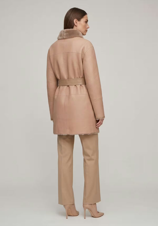 Beige women's sheepskin coat shown from the back, with belt and smooth outer surface, isolated.