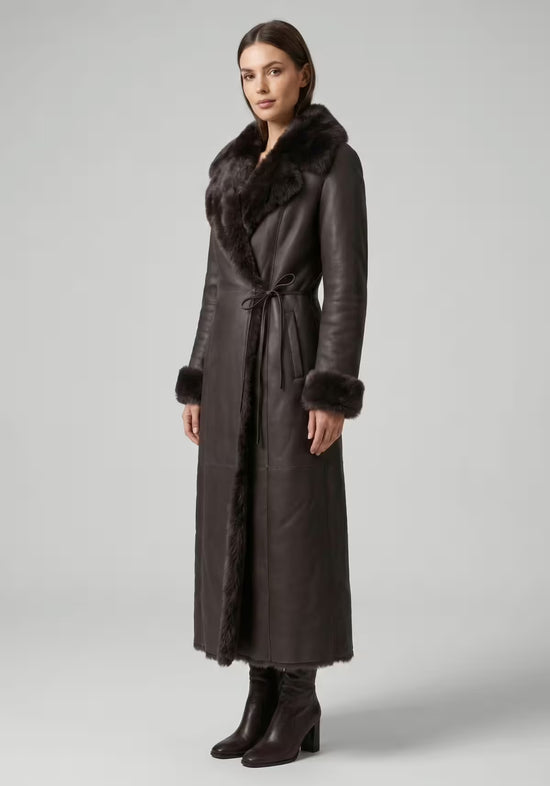 Brown sheepskin coat for women on a model in side view, with a long cut and fur trim.