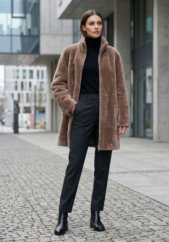 Brown worn view of the women's sheepskin coat as the reversible side, with open cut and stand-up collar.