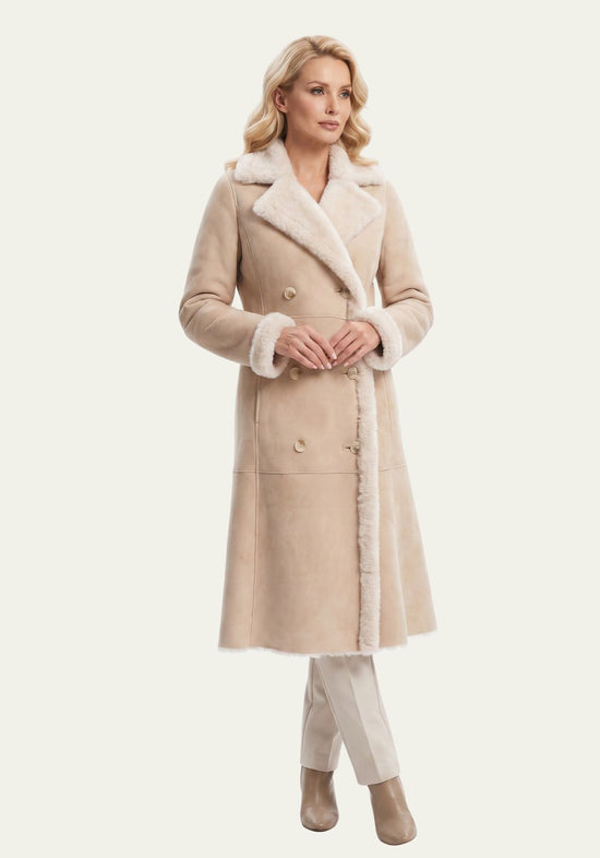 Beige women’s sheepskin coat worn closed, with wide lapels and turned-up cuffs.