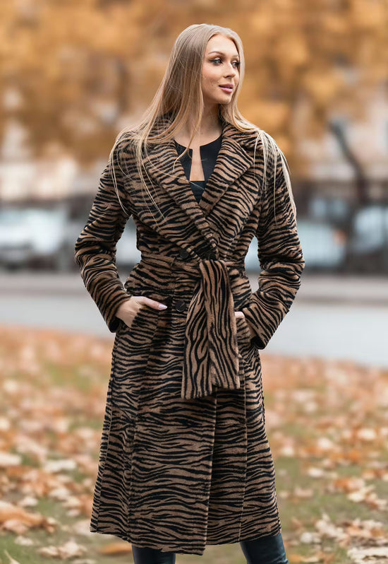 Sheepskin coat in tiger look, worn with the belt tied at the front.