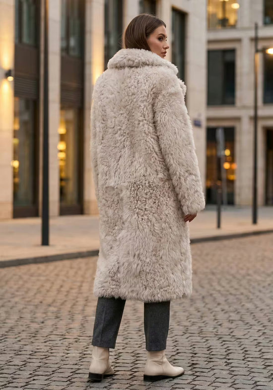 Women’s sheepskin coat made from curly sheepskin in cream-beige, worn from the back on the street.