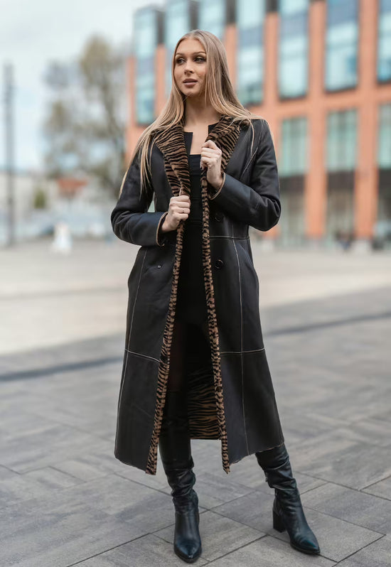 Worn sheepskin coat in black with tiger-pattern trim, worn open on the street.