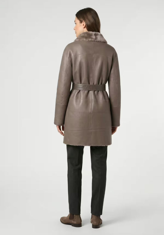 Grey-brown women’s sheepskin coat shown from the back in the leather side, with belt and straight cut.