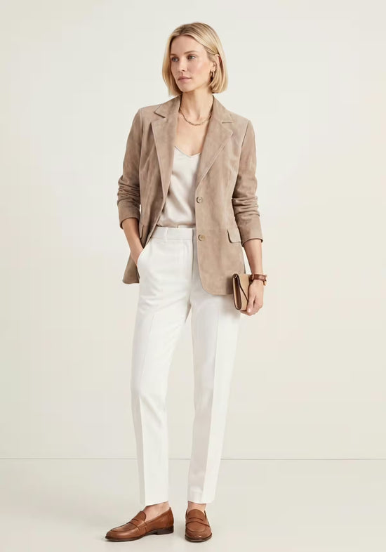 Beige women’s leather blazer in suede shown in full view, paired with light trousers.