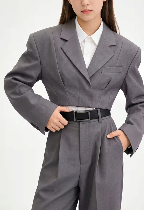 Women's leather belt made of buffalo leather in black, worn with a grey suit.