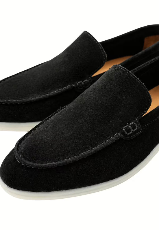 Black men’s loafers in leather, close up with decorative strap and light sole
