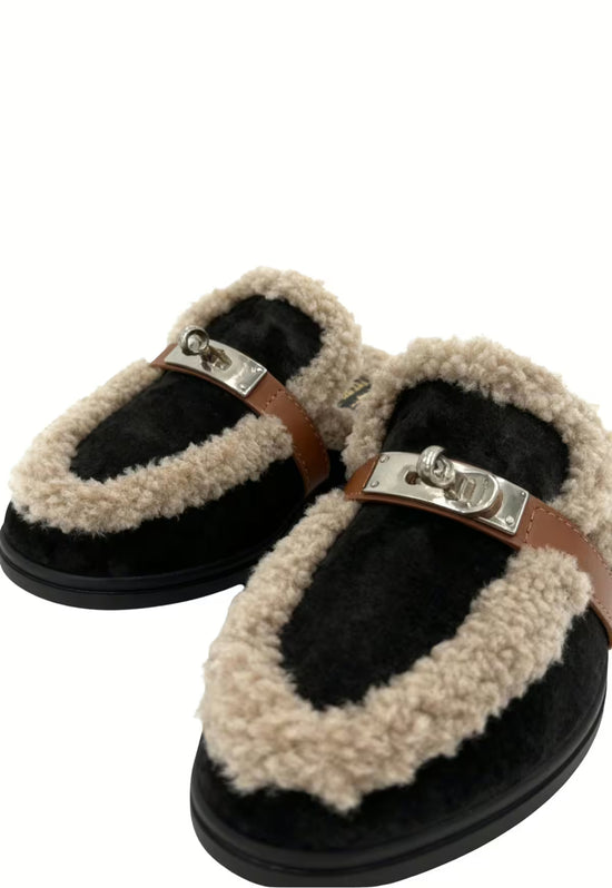 Women’s sheepskin mules in black, detail view of the front with fleece trim and metal buckle.