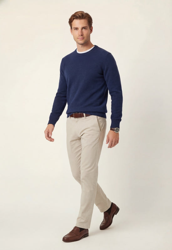 Dark navy cashmere jumper worn by a man, styled with light trousers and classic shoes.
