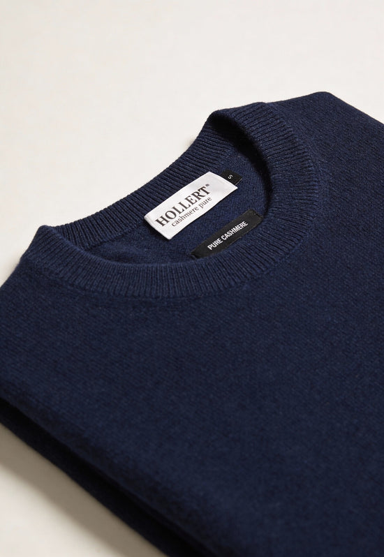 Close-up of the dark navy cashmere jumper, showing the ribbed neckline and label inside the collar.