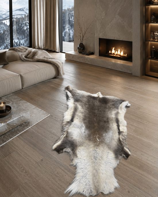Reindeer hide in cream and brown in a living room on a wooden floor by the fireplace and sofa