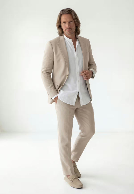 Beige men's linen blazer worn open at the front over a white shirt with matching trousers.