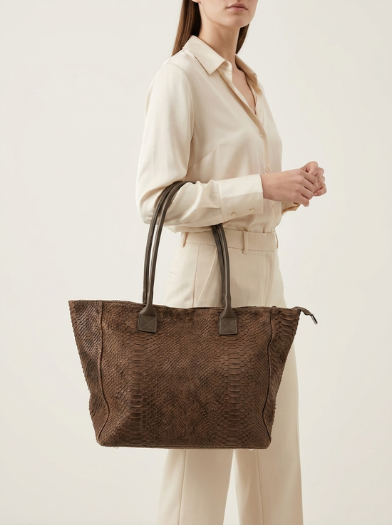 Brown women's shopper bag in suede with crocodile embossing, worn by a model