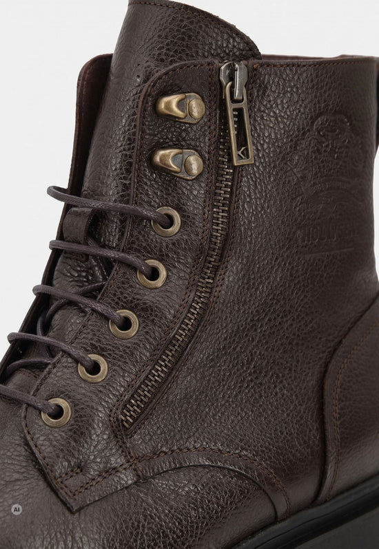 Detail of the dark brown men’s sheepskin ankle boot in leather with lacing and zip.