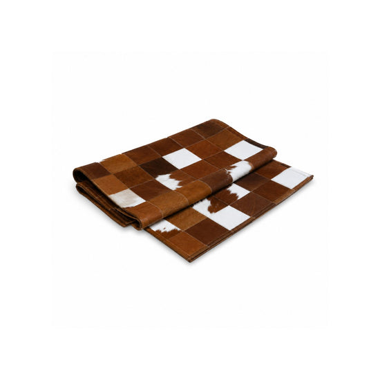 Folded brown and white cowhide rug on a white background