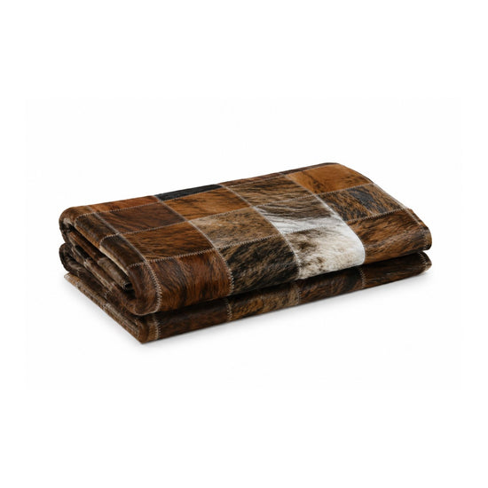 Cowhide rug folded several times in brown, white and black, isolated on a white background