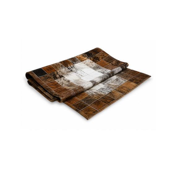 Cowhide rug in brown, white and black folded and isolated on a white background.