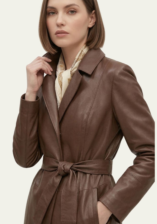 Brown women’s trench coat in lamb nappa leather, close view with tie belt, lapel collar and smooth finish.
