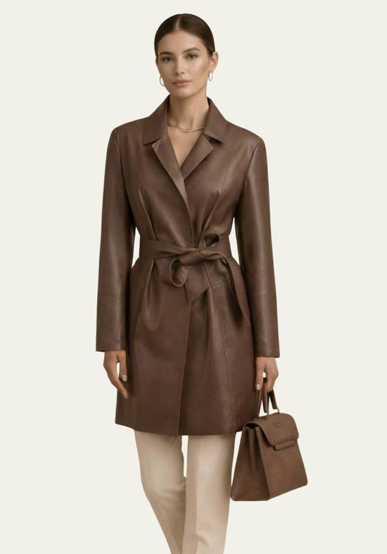 Brown women’s trench coat in lamb nappa leather, full-length view worn by a model with handbag.