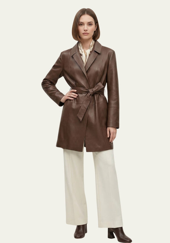 Brown women’s trench coat in lamb nappa leather, full view with model, trousers and ankle boots.