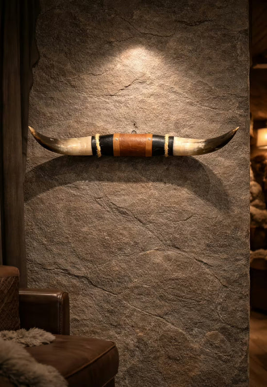 Wall decoration made of natural horn with leather and wood mount on a stone wall