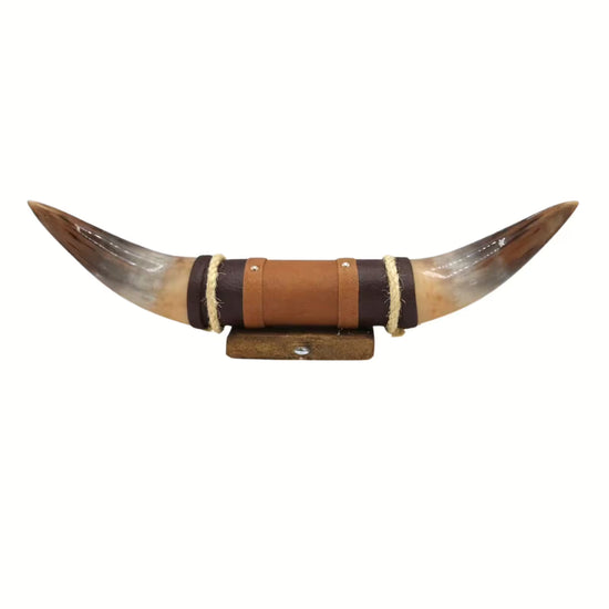 Cut-out horn wall object with brown leather holder and wooden base on a white background.