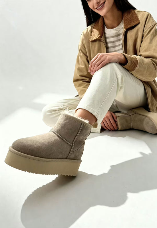 Beige sheepskin winter boot for women worn on foot with a visible high shaft