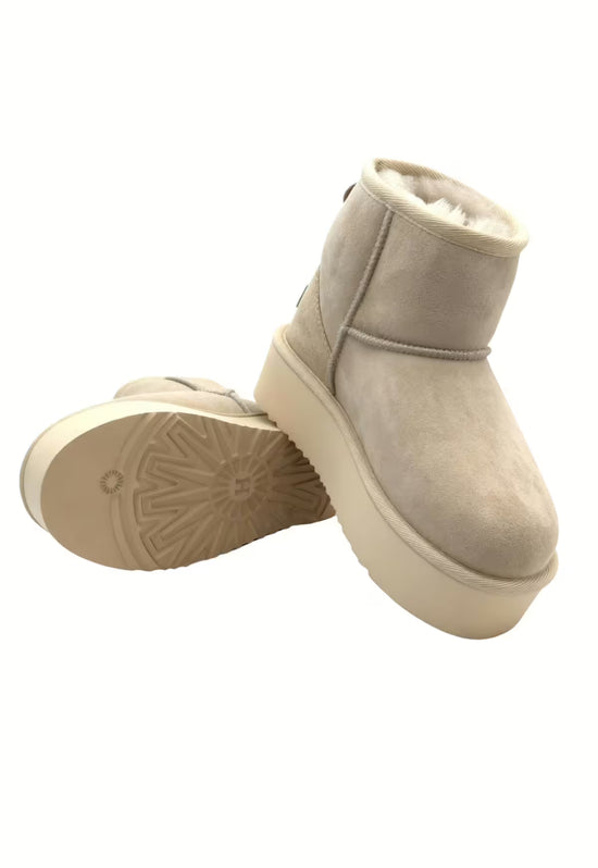 Beige women's winter boot in sheepskin, angled view with the tread sole visible